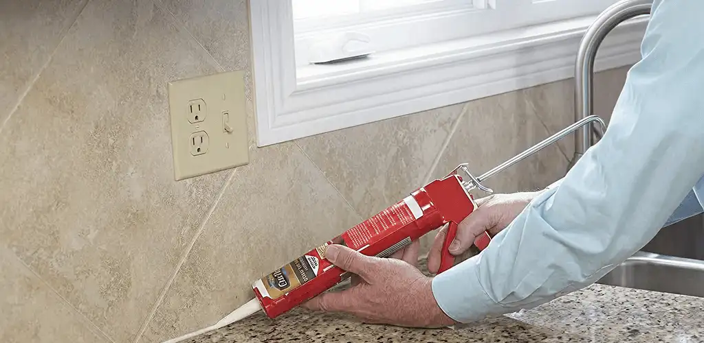 Handyman applying caulk along a kitchen backsplash and countertop seam in Staten Island, NY