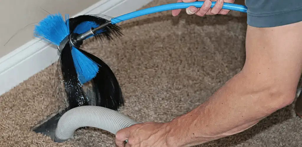 Dryer vent cleaning technician brushing lint from a vent line in Staten Island, NY