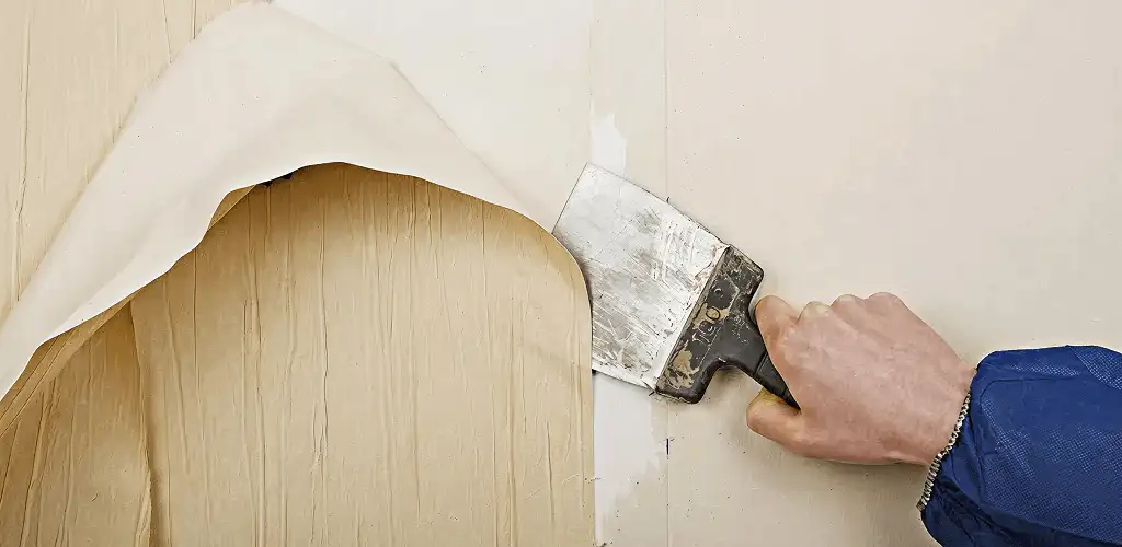 Handyman removing wallpaper with a scraper for wall preparation in Staten Island, NY
