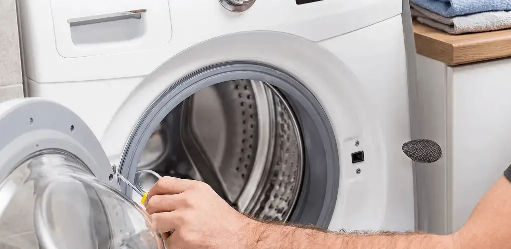 Handyman repairing a front-load washing machine and inspecting the drum in Staten Island, NY
