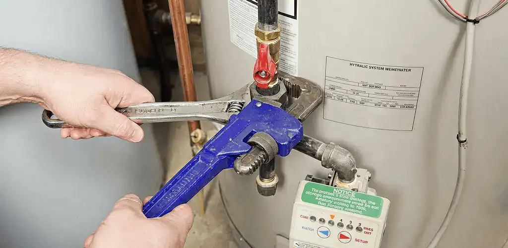 Water heater repair technician tightening the shutoff valve and supply line in Staten Island, NY